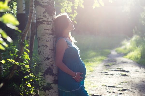 pregnant woman leaning against tree